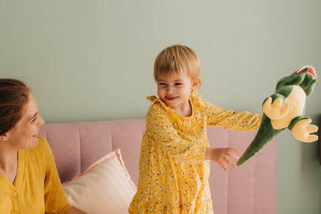 fillette qui joue avec un dinosaure en peluche