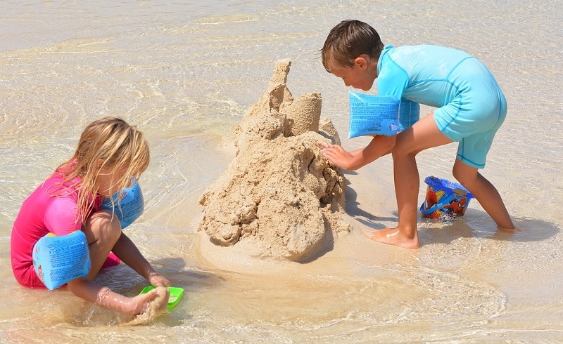 garçons heureux faisant un château de sable sur la plage