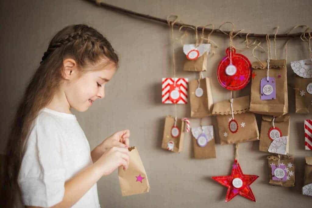 fille ouvre calendrier de l'avent maison