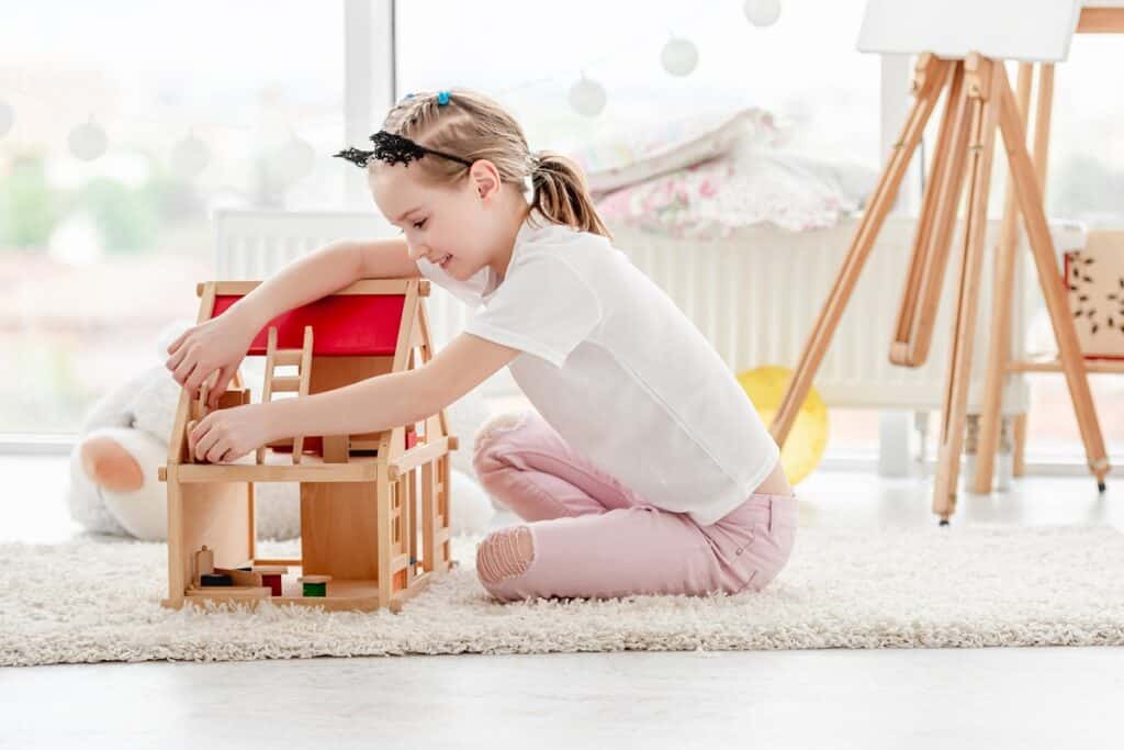 fille qui joue avec maison de poupée en bois