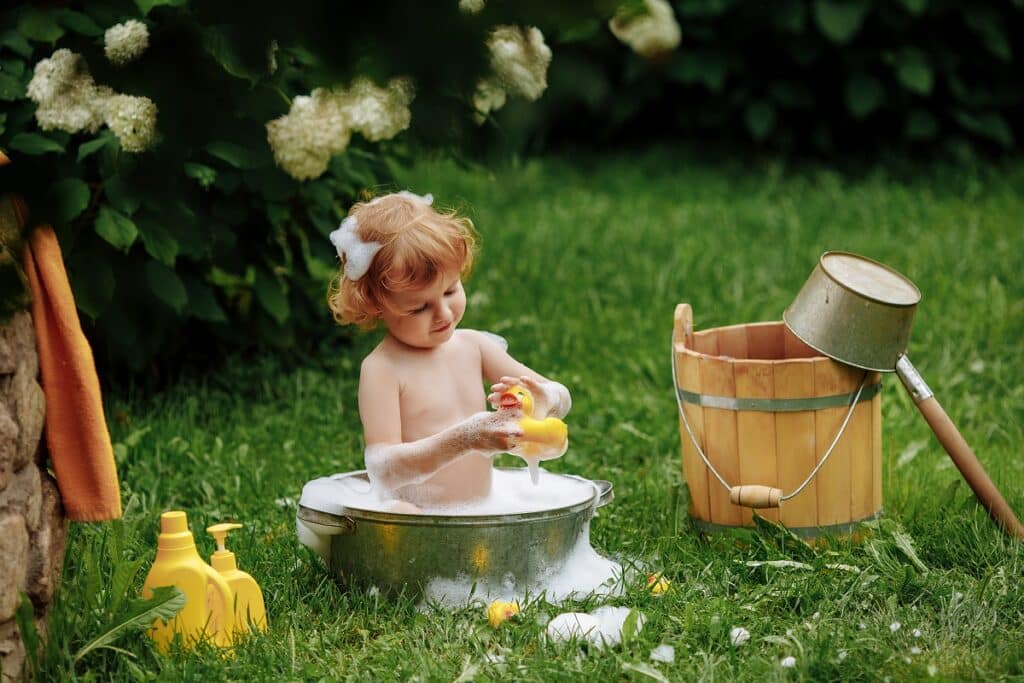 petite fille jouant dans un jardin bassine eau