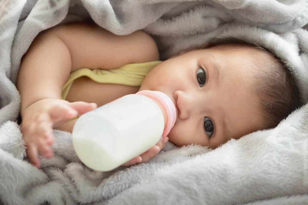 bébé boit biberon de lait