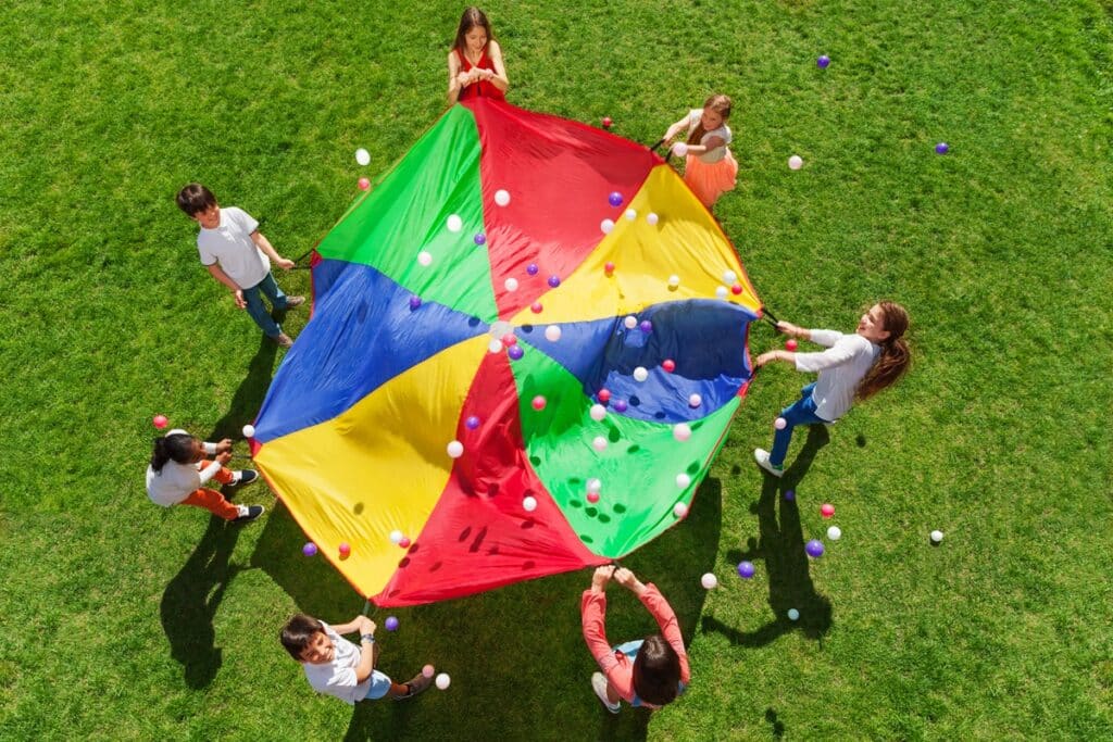 les enfants font sauter des balles sur un parachute