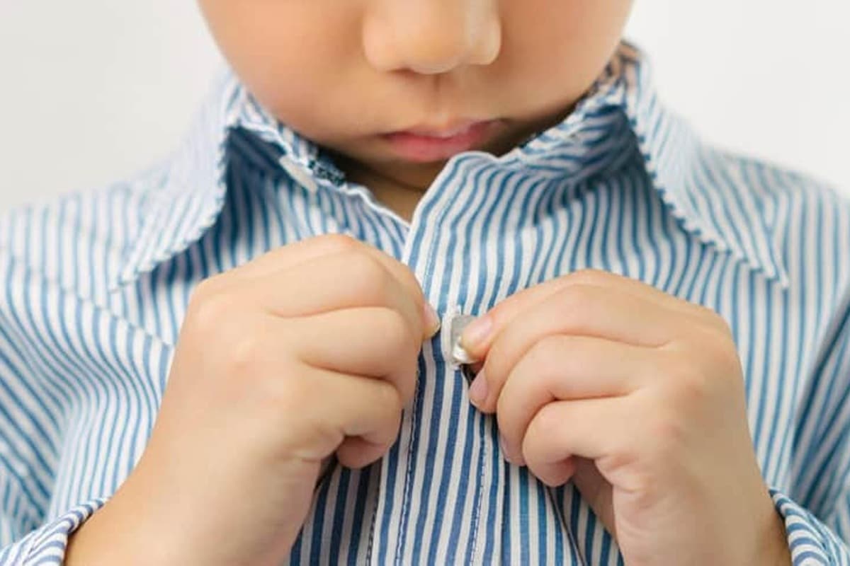 jeune enfant boutonne sa chemise